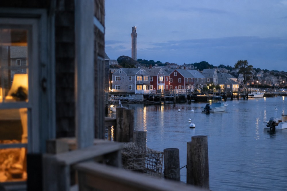 Colorful waterfront buildings along Provincetown harbor with boats moored in calm water