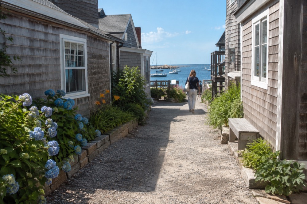 A narrow lane of small wooden shops leading toward the ocean in a coastal village