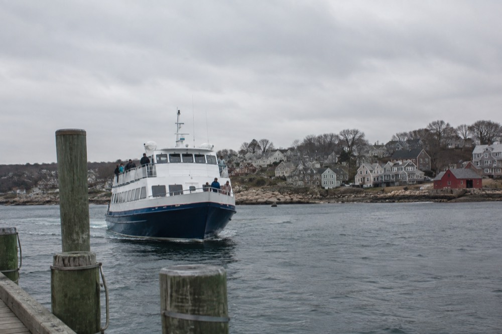 A passenger ferry approaching a dock with a coastal town visible behind it