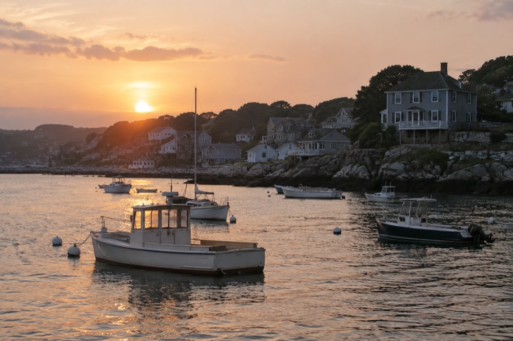 A small coastal town seen from the water at sunset with boats in the foreground