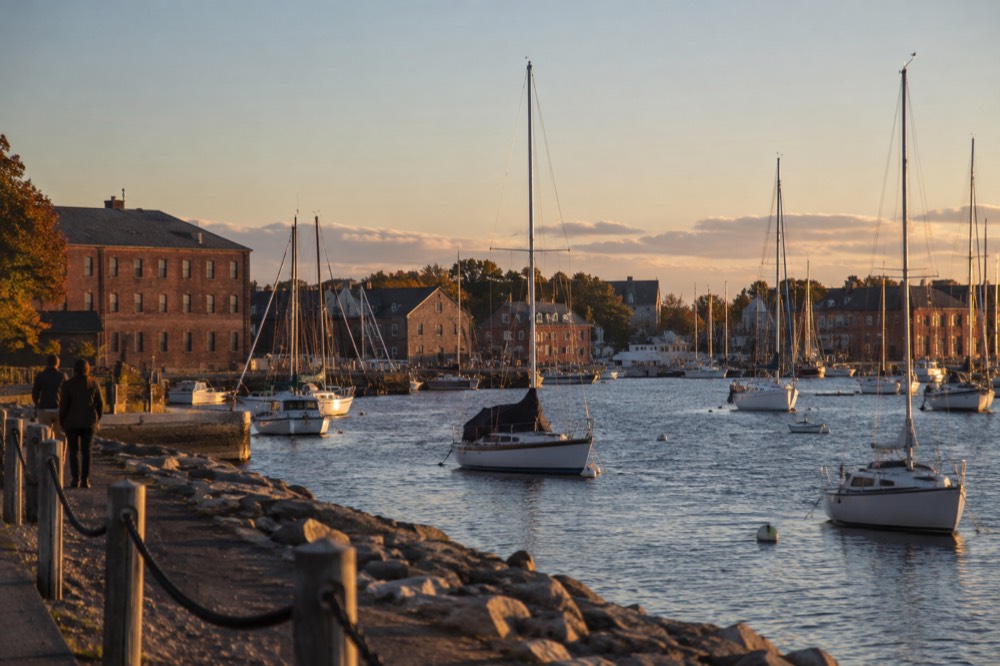 Harbor waterfront with masts and brick warehouses on a clear afternoon