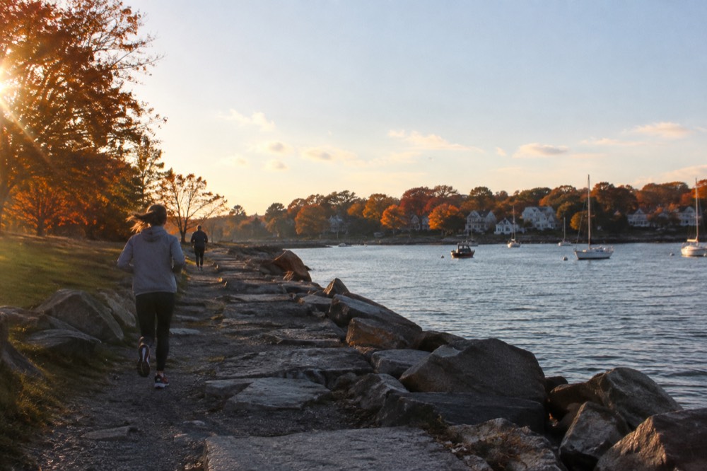 Coastal town viewed from the water with autumn trees along the shore