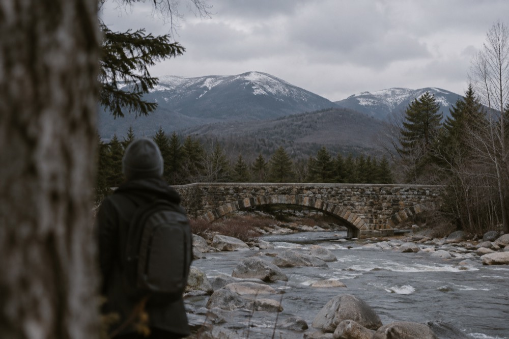 A stone bridge over a river with mountains in the background