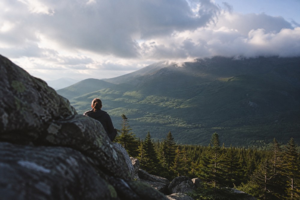 Clouds moving across a green mountain ridge with patches of sunlight