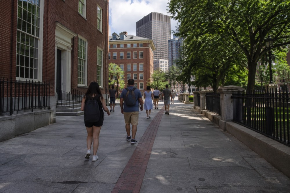 Visitors walking the red brick line of the Freedom Trail past historic Boston buildings