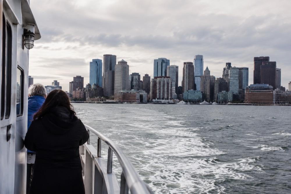 A whale watching boat heading out of Boston Harbor past the skyline