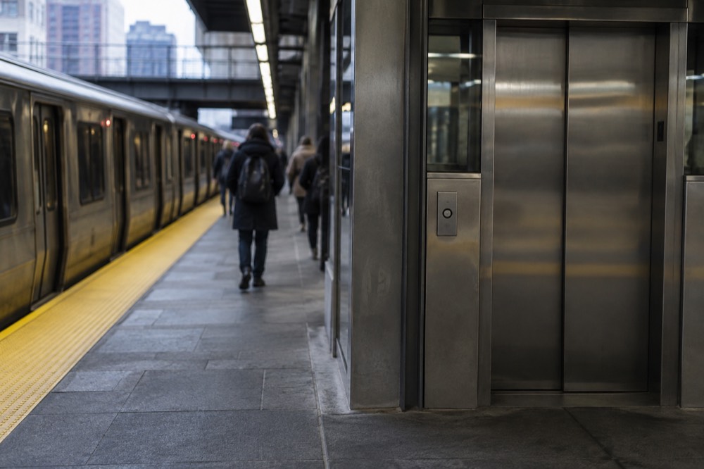 A modern subway platform with a marked gap filler strip and elevator doors