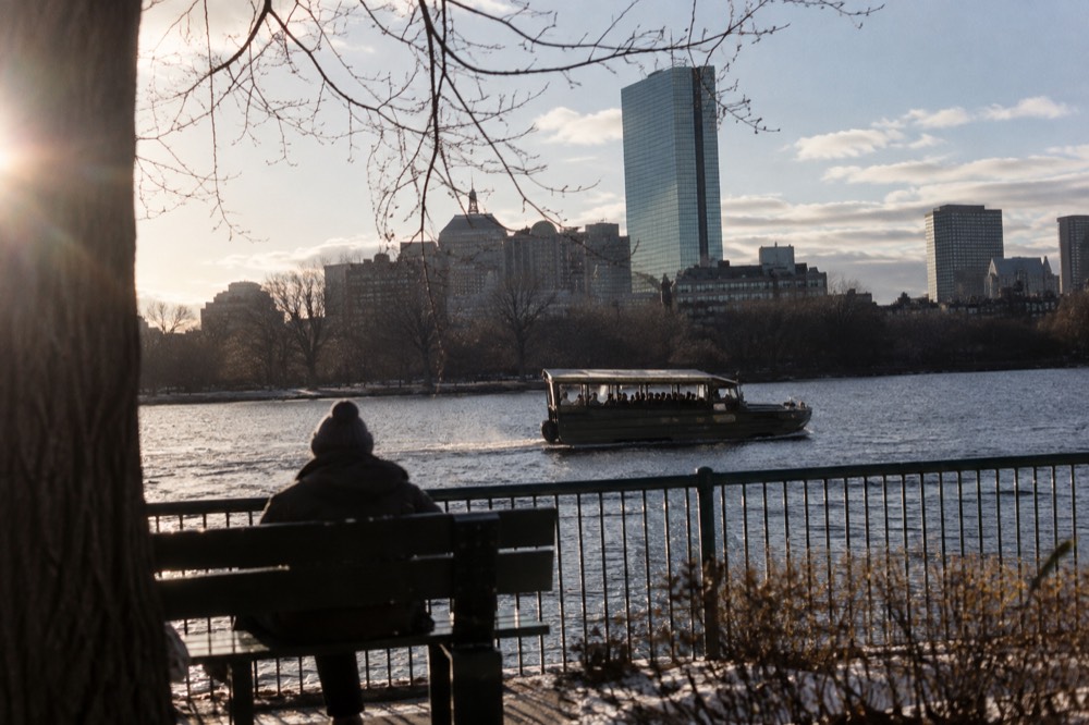 An amphibious duck boat cruising on the Charles River with the city behind it