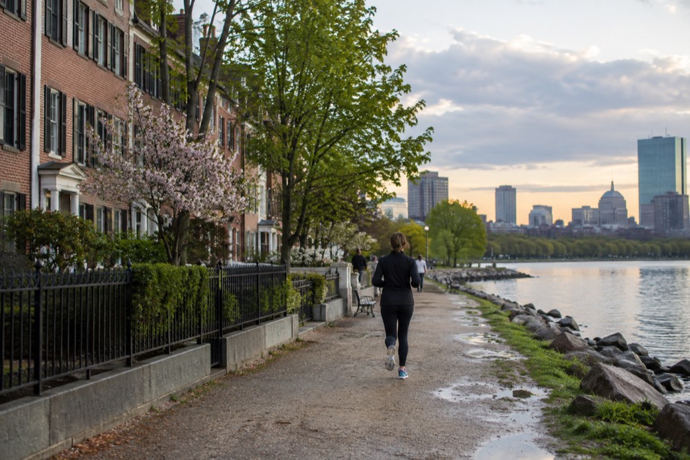 A row of brick rowhouses near a waterfront street with a beach path leading toward the water