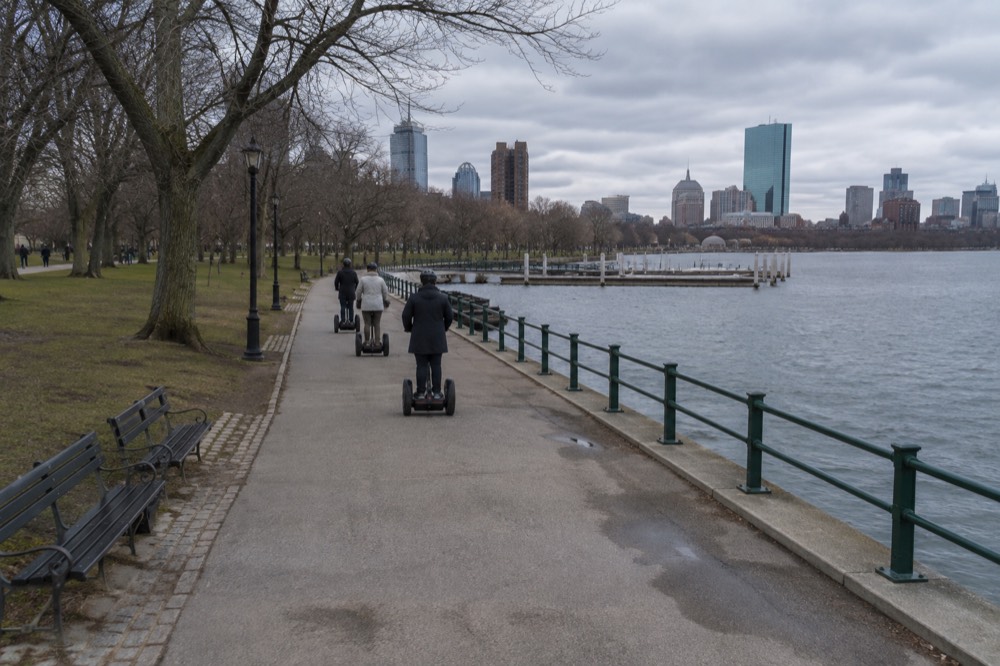 A small group gliding on Segways along a wide waterfront promenade