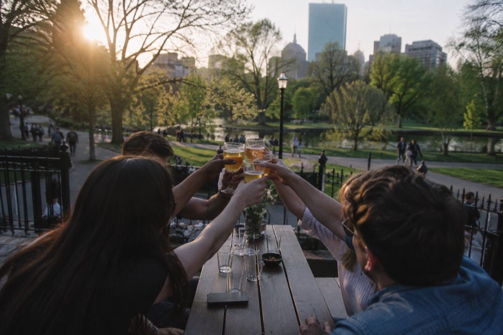 A group of friends clinking glasses across a long taproom table