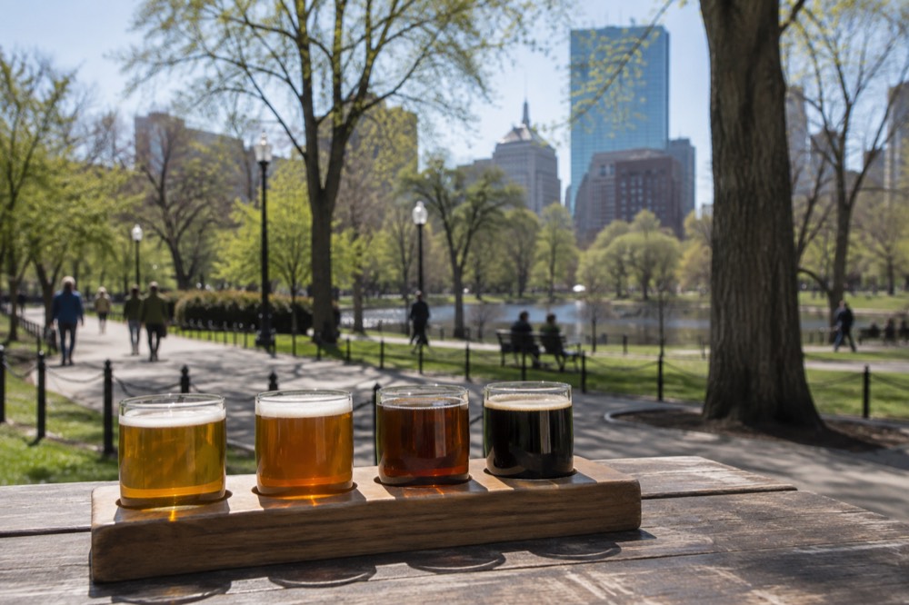 A flight of four small beer samples arranged on a wooden tasting tray