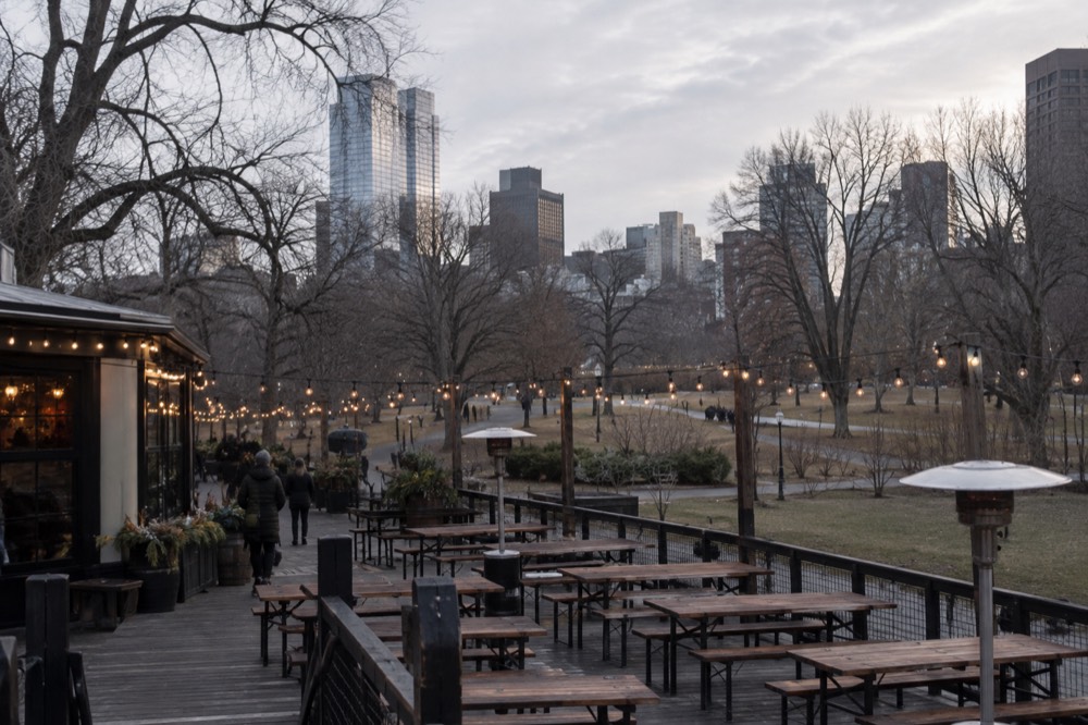 A brewery beer garden with string lights and empty benches under a gray winter sky