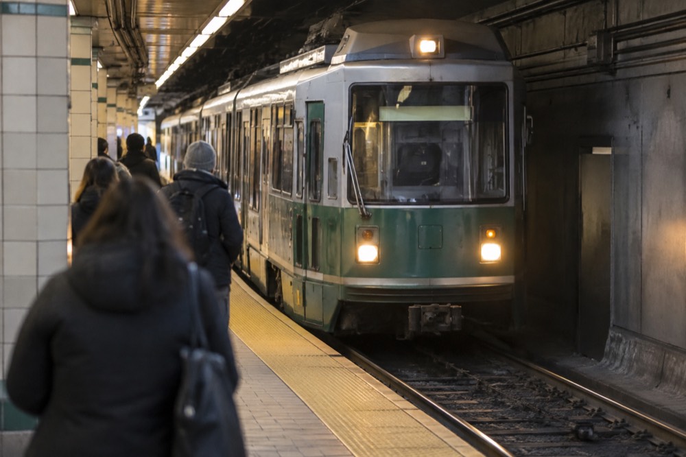 A green line trolley arriving at an underground station platform with tiled walls