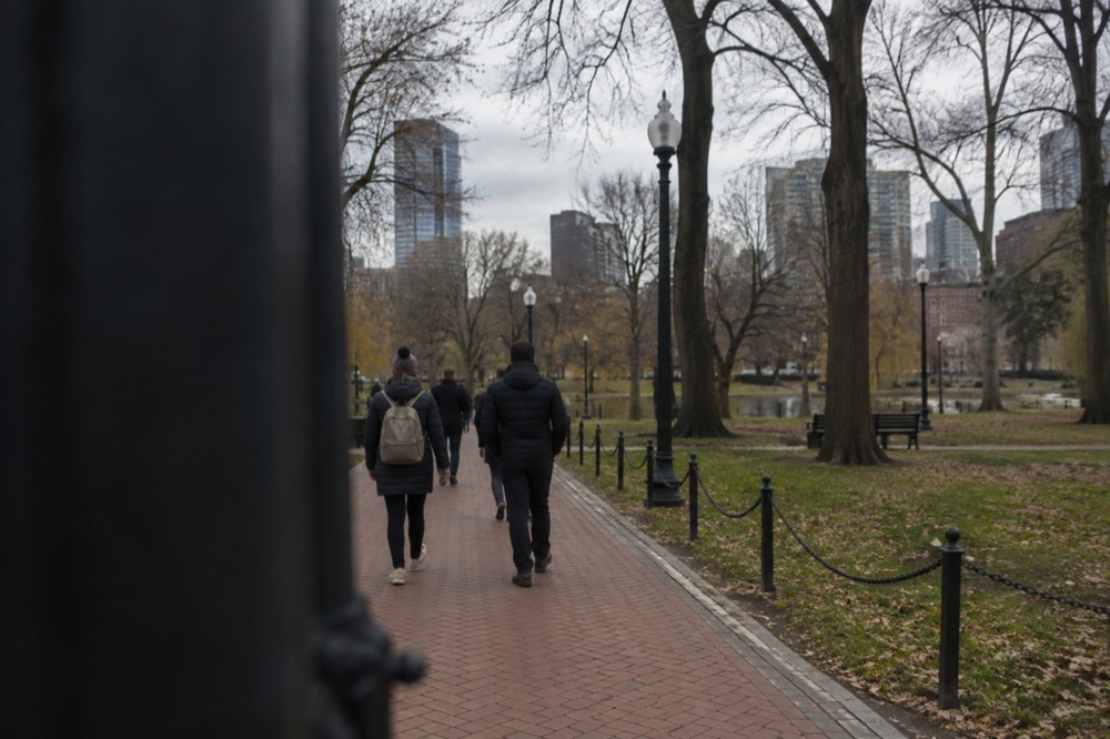 People walking a red brick line through a historic Boston street