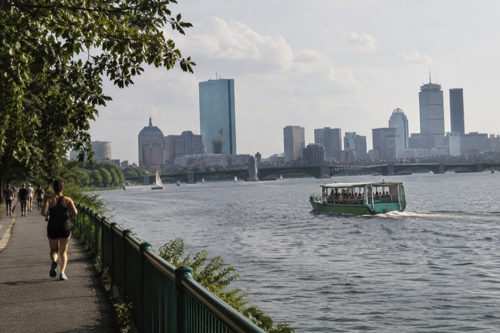 An amphibious duck boat cruising across the Charles River with the Boston skyline behind it