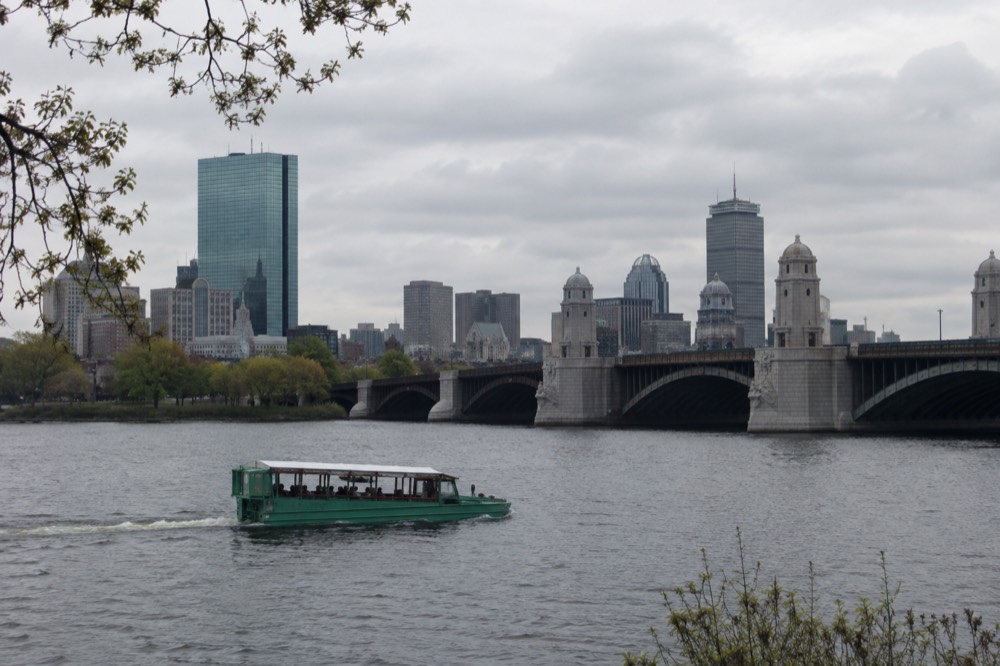 A duck boat floating on the Charles River with the Longfellow Bridge and skyline in the background