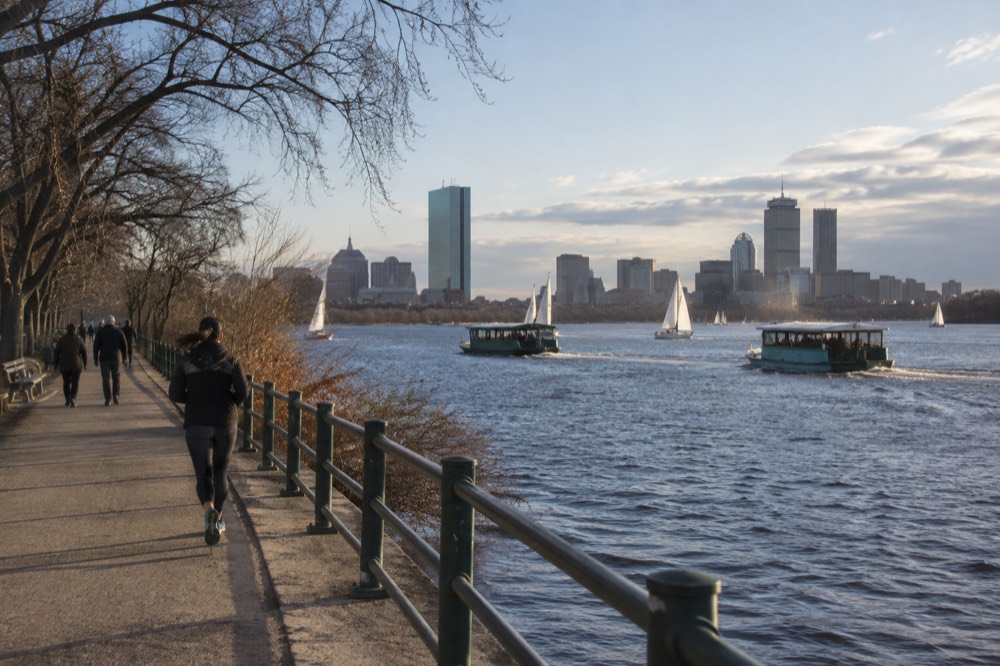 Two duck boats on the Charles River passing sailboats near the Esplanade