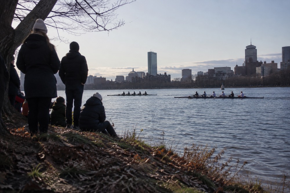 Rowing shells racing on the Charles River with spectators on the banks