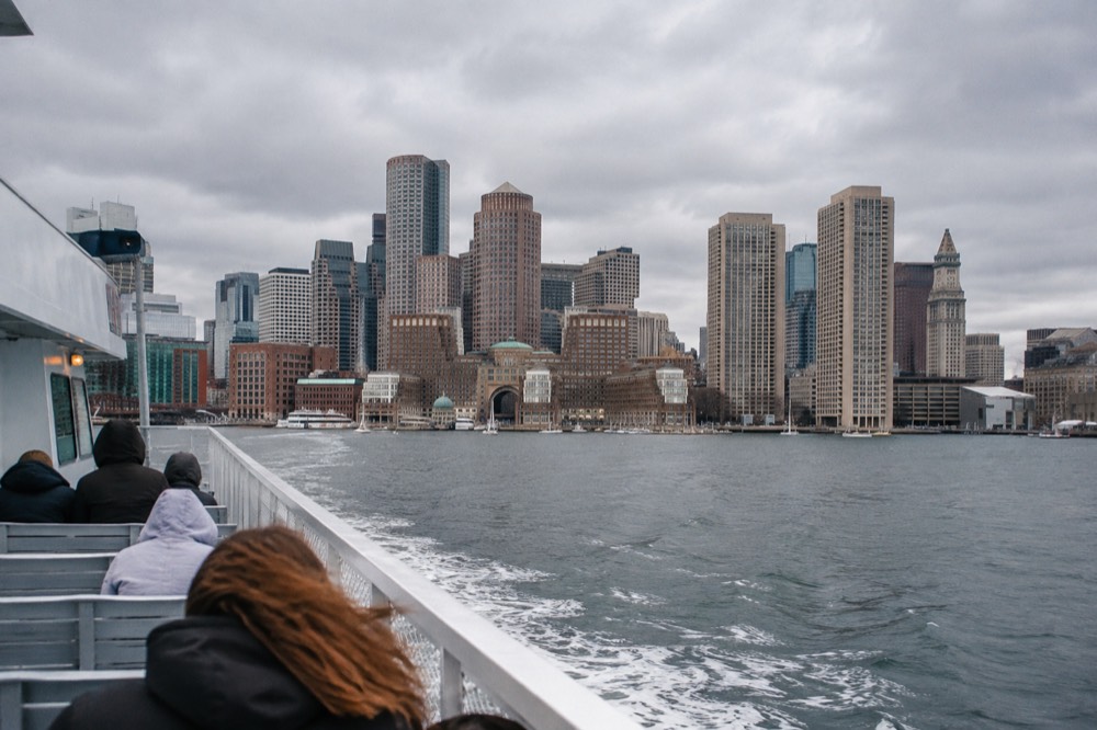 A ferry crossing Boston Harbor with the downtown skyline behind it