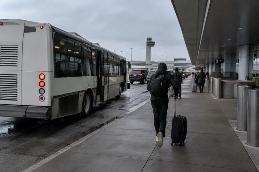 An airport shuttle bus at a Logan Airport terminal curb