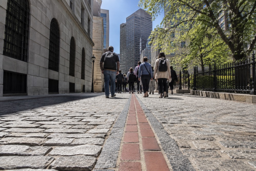 A guided walking group following the red Freedom Trail line in downtown Boston