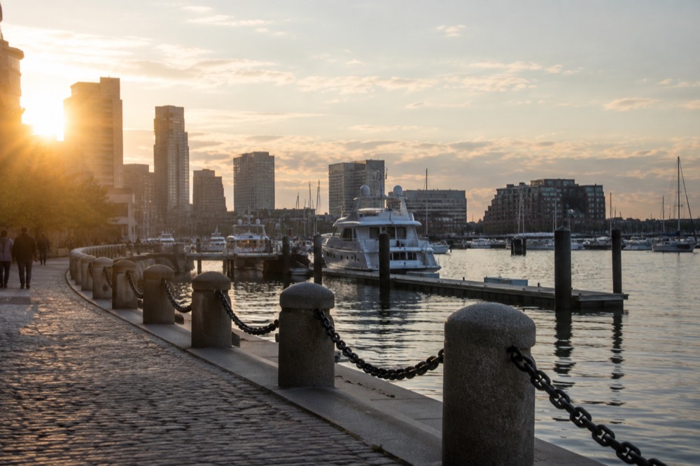 The Boston Harborwalk curving along the water with boats moored nearby