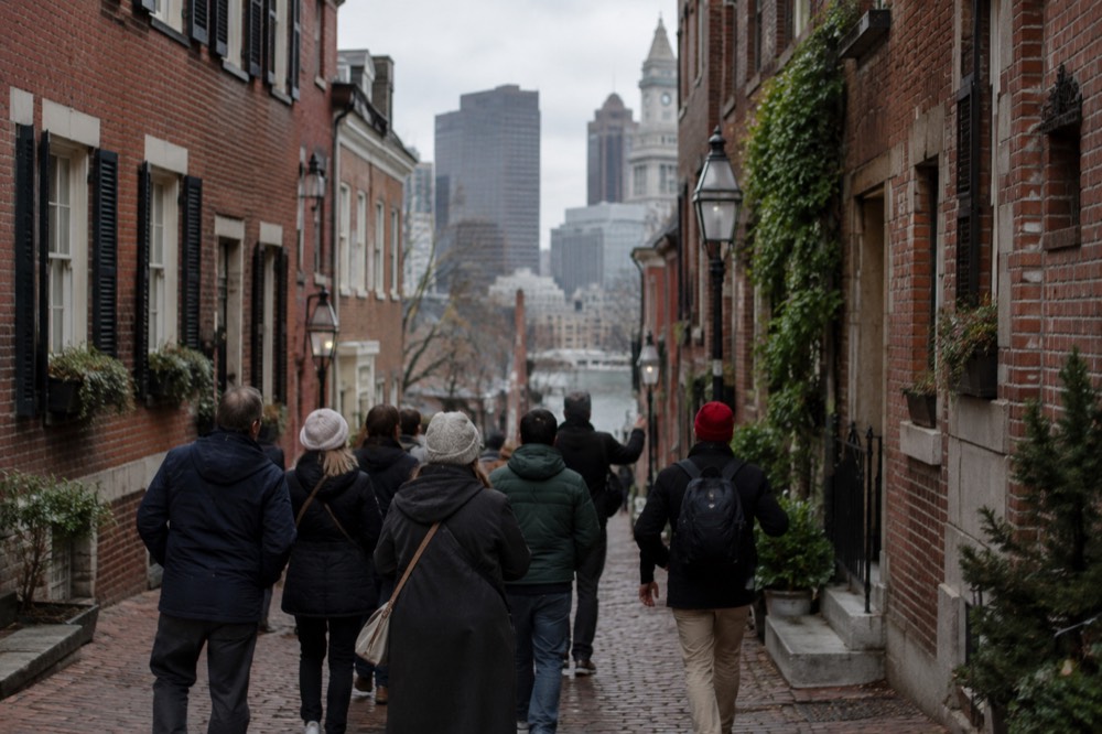 A guide leading a small group of visitors down a narrow brick street in Boston's North End