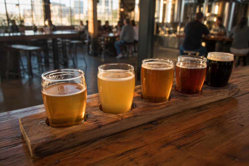 A flight of beer glasses on a wooden bar inside a Boston brewery taproom