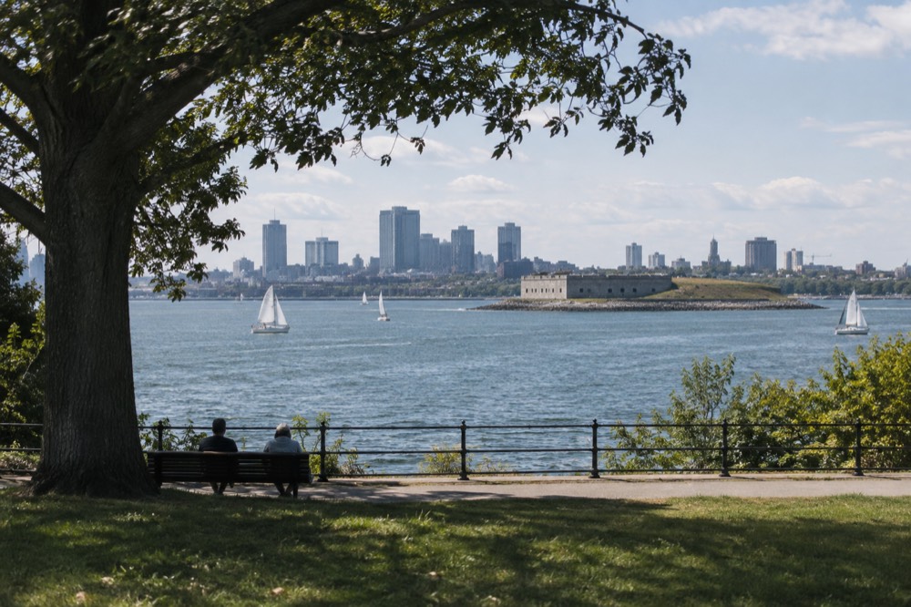 A stone fort on a green peninsula overlooking a harbor with sailboats