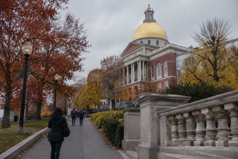 The golden dome of the Massachusetts State House against red and orange autumn foliage