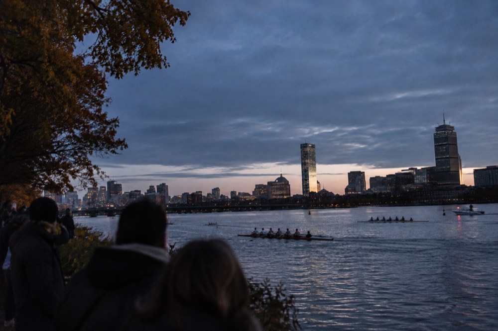 Rowers on the Charles River during a fall regatta with spectators on the banks