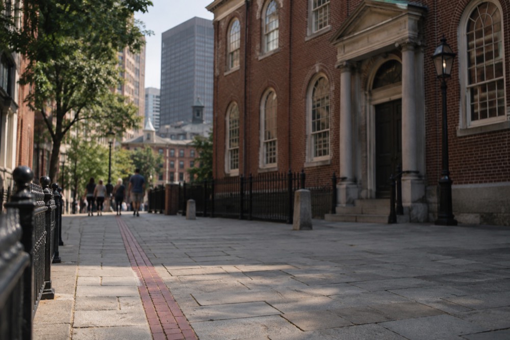 A red-brick Freedom Trail line leading past a historic Boston church facade