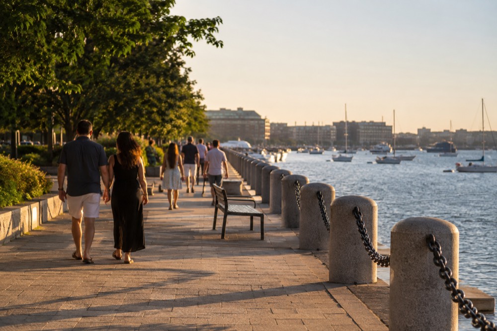 People walking along the Boston Harborwalk on a bright summer day