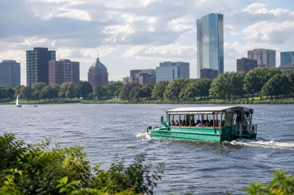 An amphibious duck boat cruising on the Charles River with the city behind it