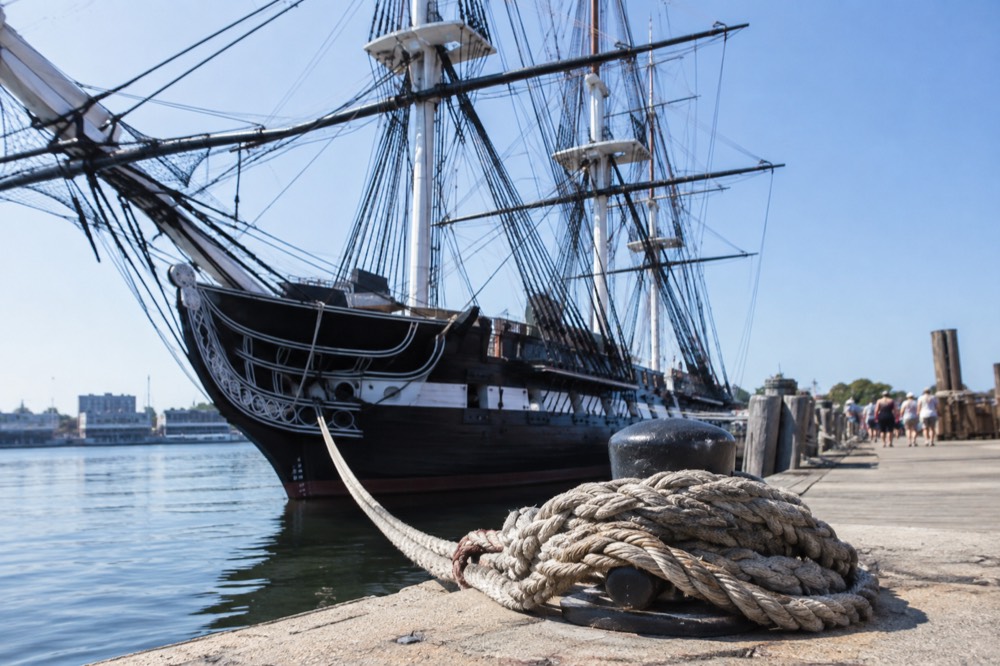 The USS Constitution docked at the Charlestown Navy Yard under a clear sky