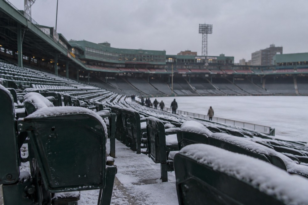 Fenway Park's green seats dusted with snow under an overcast sky