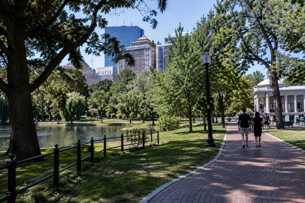 Visitors walk a red-brick pedestrian lane past historic colonial-era buildings