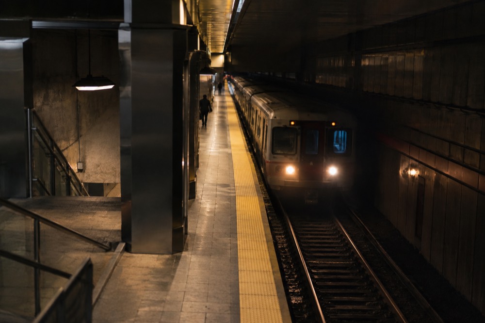 An empty subway platform at night with a train arriving