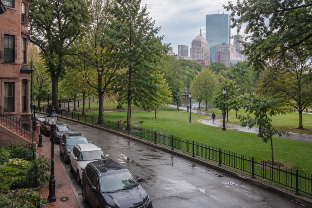 A row of parked cars beside a brownstone building on a Boston residential street