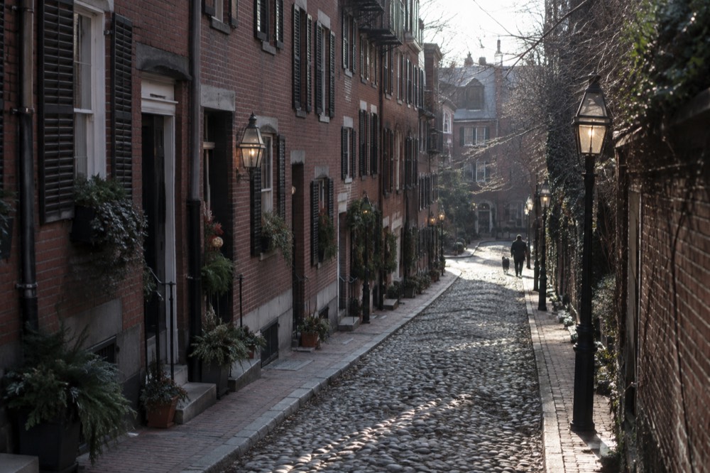 Cobblestone Acorn Street in Beacon Hill with brick rowhouses and gas lamps in morning light