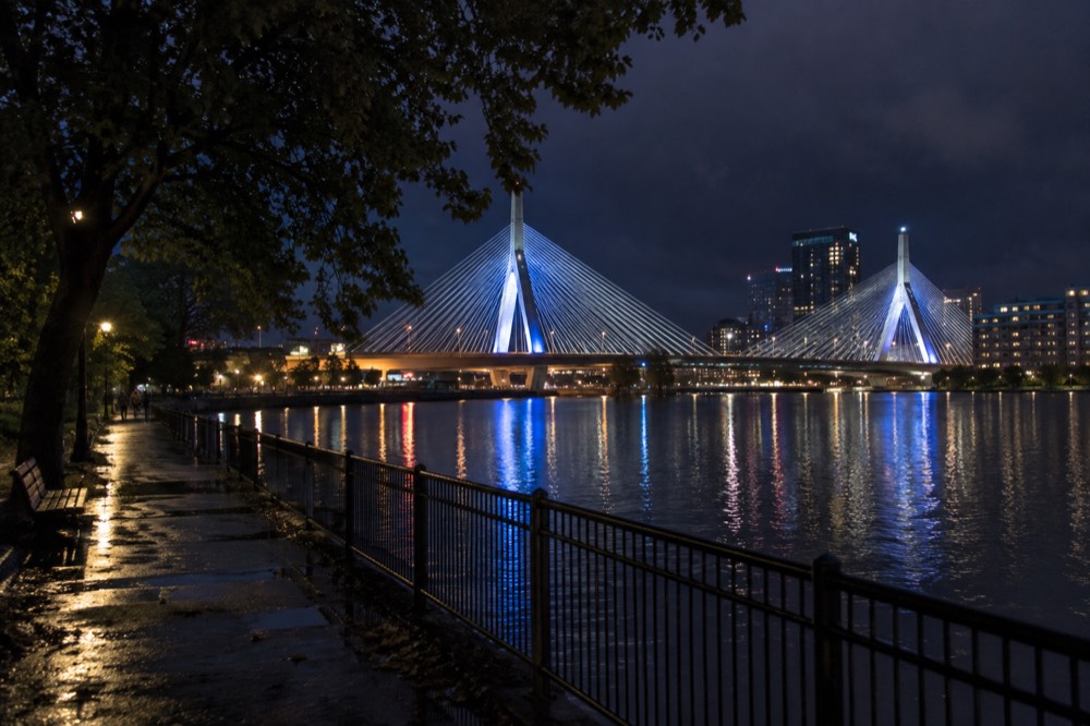 Zakim Bridge lit in blue and white lights reflected in the Charles River at night