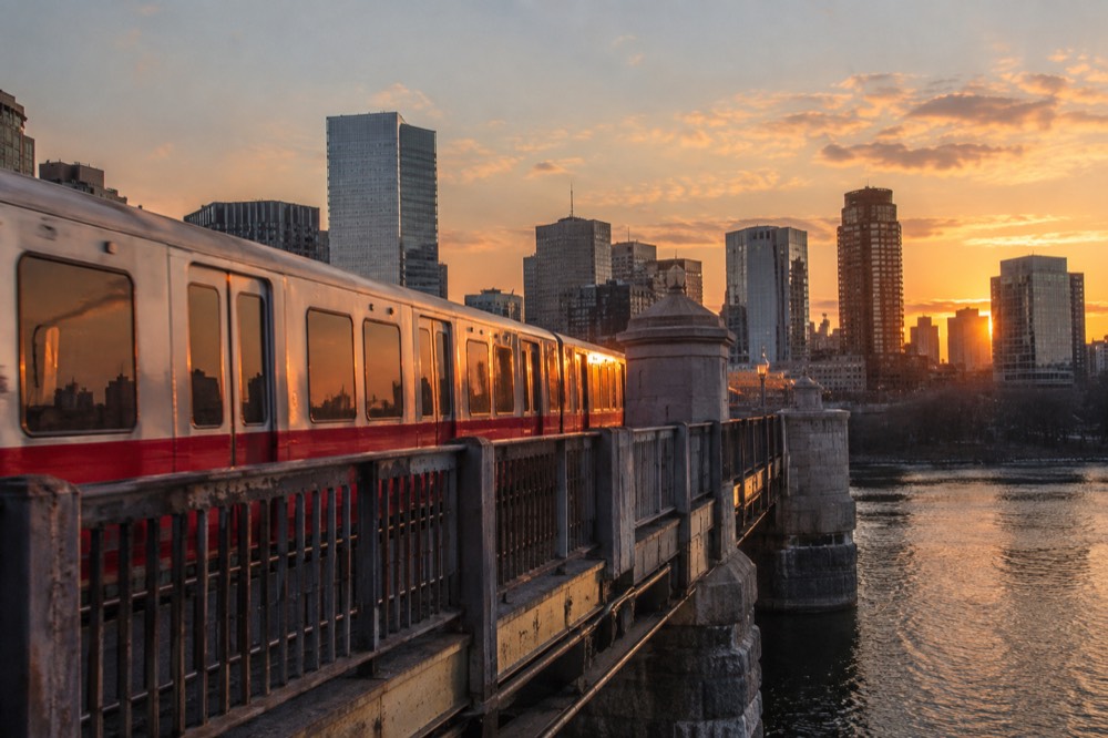 Red Line train crossing the Longfellow Bridge toward Boston at sunset with skyline behind