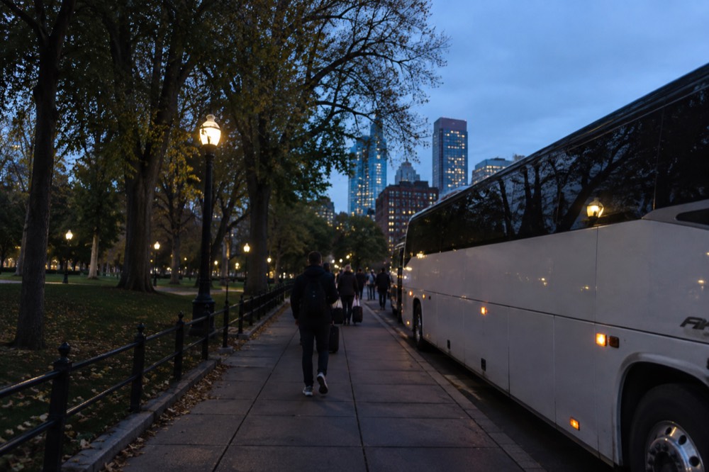 An intercity bus parked at a curbside pickup area near a city station
