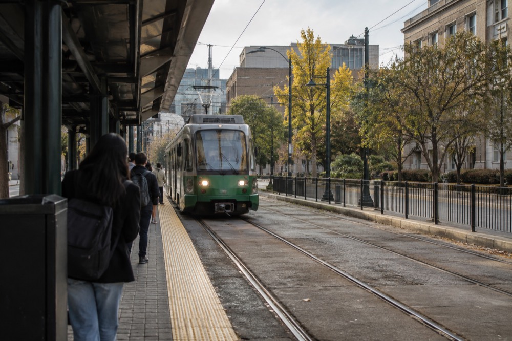 Green Line trolley arriving at a street-level station near campus buildings
