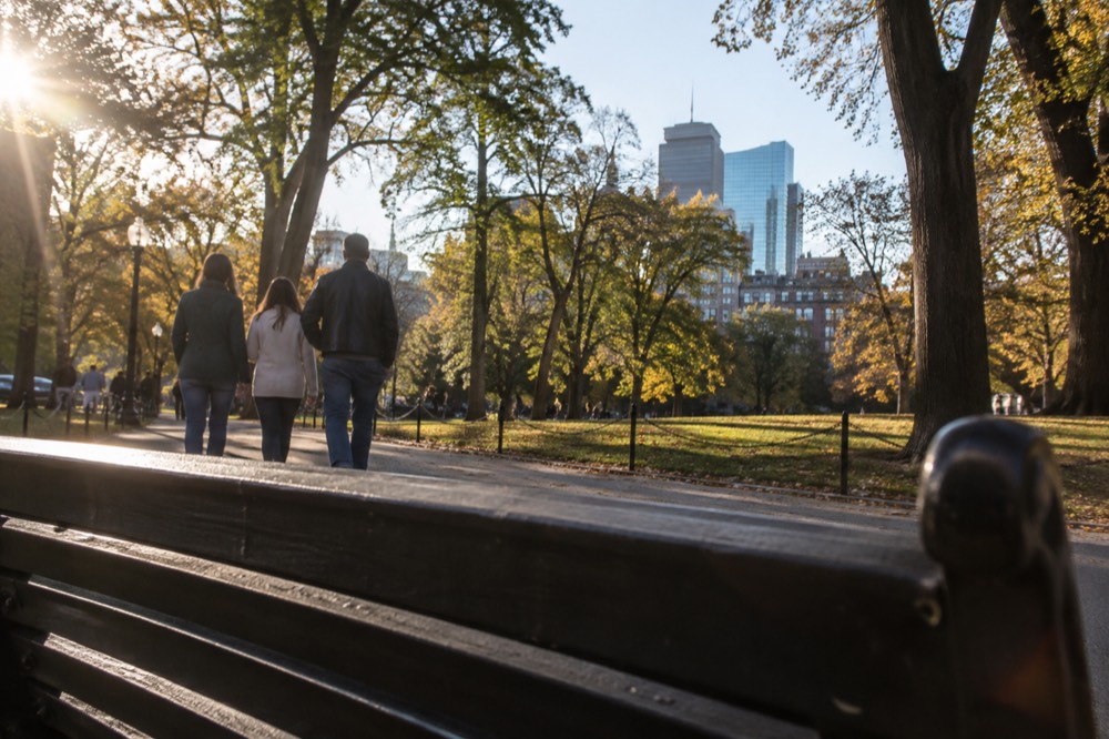 Family with a teenager looking at a campus map on a bench