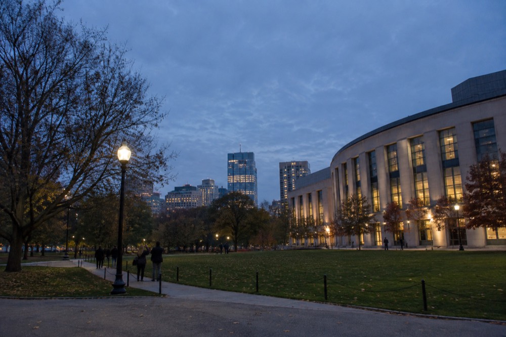 Modern curved academic building beside a lawn with visitors taking photos