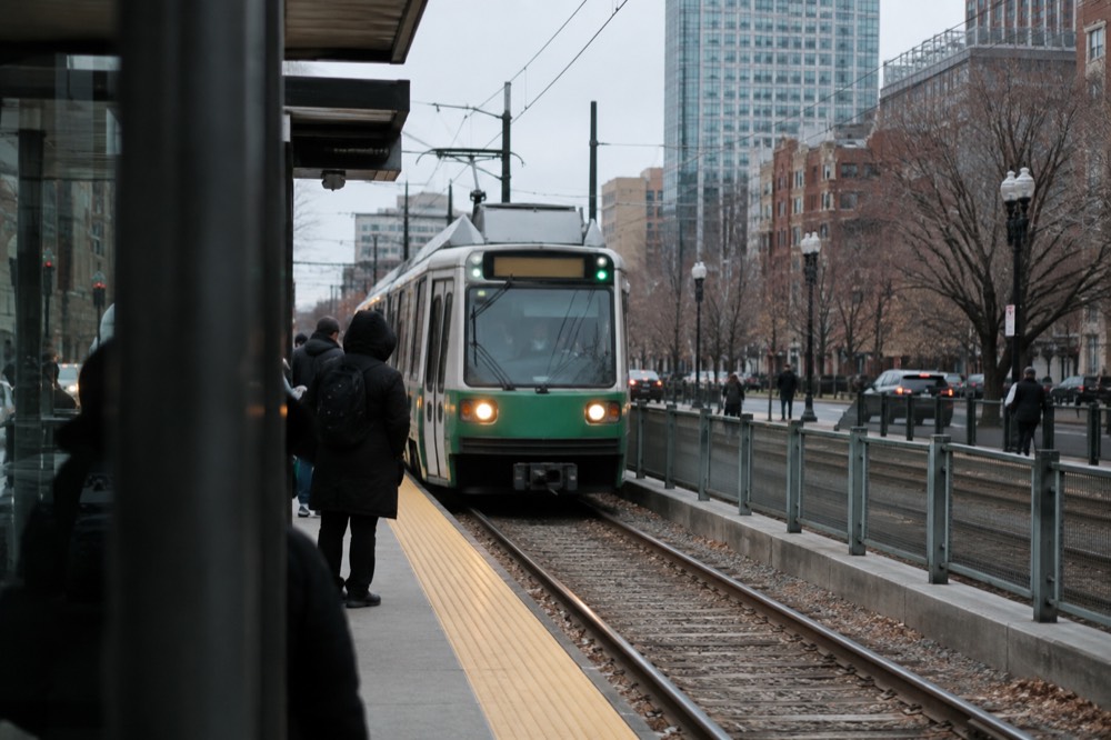 A Green Line trolley arriving at a street-level MBTA station in Boston