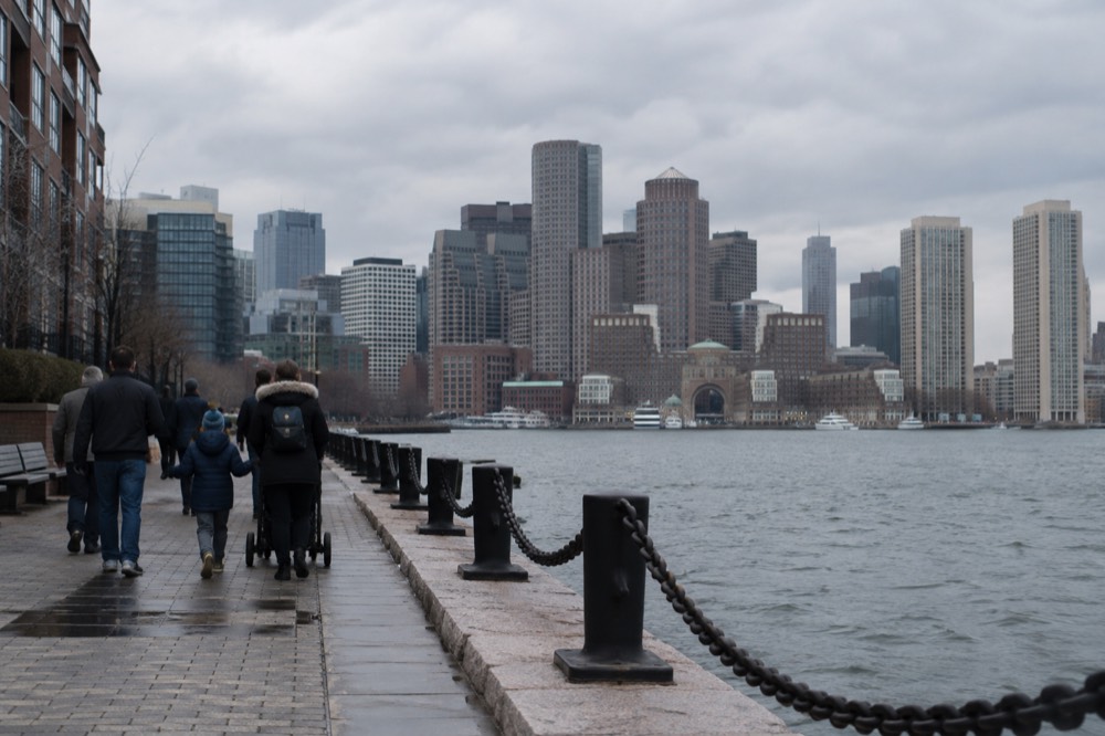 Families walking along the Harborwalk with the Boston skyline behind them