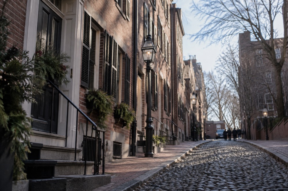 Brownstone facades on a Beacon Hill street under clearing skies